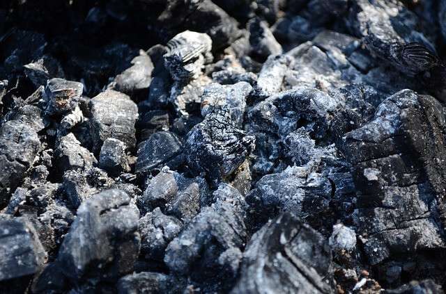 Holzasche mit Glutresten in einer Feuerstelle